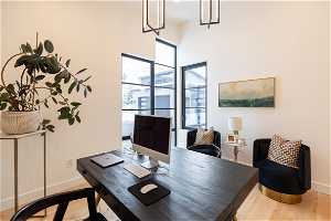 Office with plenty of natural light, a high ceiling, and light hardwood / wood-style flooring
