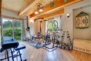 Exercise area with light hardwood / wood-style flooring, wooden ceiling, and a healthy amount of sunlight