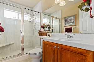 Bathroom featuring an enclosed shower, toilet, tile flooring, and vanity with extensive cabinet space