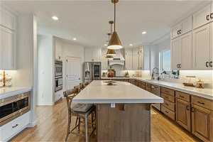 Kitchen featuring a kitchen island, light hardwood / wood-style flooring, white cabinets, and stainless steel appliances