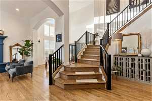 Stairway with light hardwood / wood-style floors and a high ceiling