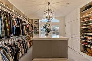 Walk in closet with a chandelier and light carpet
