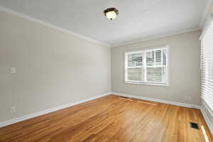 Unfurnished room with ornamental molding and wood-type flooring