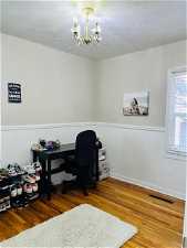 Bedroom/Office area with hardwood / wood-style flooring, an inviting chandelier, and a textured ceiling