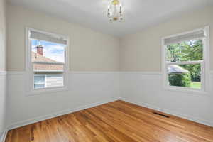 Spare room featuring light hardwood / wood-style floors, a wealth of natural light, and a chandelier