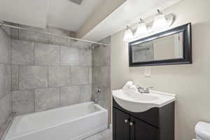 Full bathroom featuring vanity, tile floors, toilet, and tiled shower / bath combo