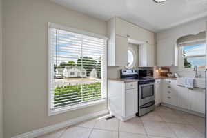 Kitchen with a wealth of natural light, appliances with stainless steel finishes, sink, and light tile flooring