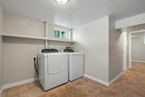 Laundry area with washing machine and dryer, a textured ceiling, light colored carpet, and electric dryer hookup