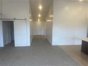 Spare room with a barn door and dark colored carpet