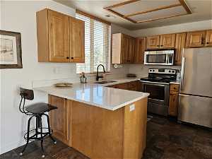Kitchen featuring kitchen peninsula, dark tile floors, stainless steel appliances, and sink