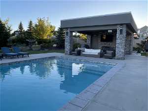 View of swimming pool featuring an outdoor living space with a fireplace and a patio