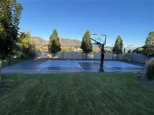 View of basketball court with a mountain view and a lawn