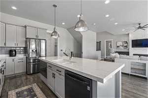 Kitchen with ceiling fan, sink, a kitchen island with sink, stainless steel appliances, and pendant lighting