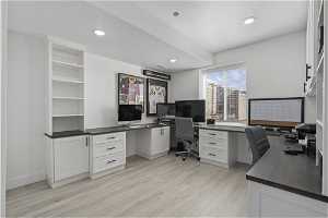 Office area featuring a textured ceiling, built in desk, and light hardwood / wood-style floors