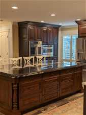 Kitchen with appliances with stainless steel finishes, crown molding, and dark stone counters