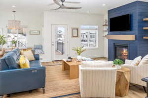 Living room with a fireplace, ceiling fan with notable chandelier, and light LVP floors