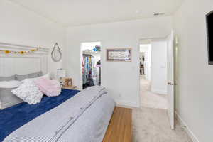 Carpeted bedroom with a spacious closet and a closet