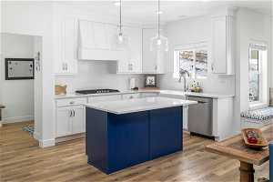 Kitchen with a center island, white cabinetry, dishwasher, and light LVP floors