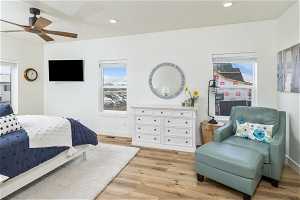 Master bedroom with light LVP floors, multiple windows, and ceiling fan