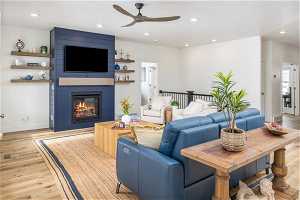Living room with a fireplace, ceiling fan, and light LVP floors