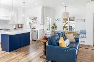 Kitchen with white cabinets, light LVP floors, a chandelier, and stainless steel dishwasher