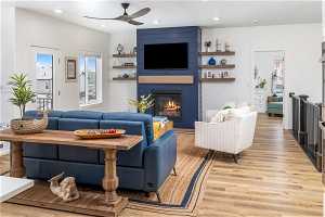 Living room with light LVP flooring, a fireplace, and ceiling fan