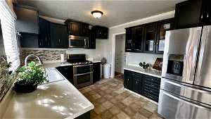 Kitchen featuring sink, light tile floors, backsplash, stainless steel appliances, and crown molding