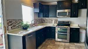 Kitchen with sink, tasteful backsplash, stainless steel appliances, and light tile floors