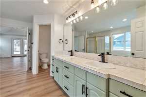 Bathroom with toilet, wood-type flooring, and dual bowl vanity