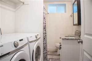 Clothes washing area with sink, tile flooring, and washing machine and dryer