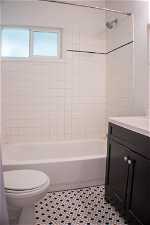 Full bathroom featuring tiled shower / bath, vanity, toilet, and tile flooring