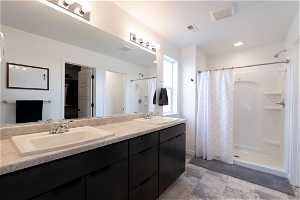 Owner's Bathroom featuring large walk-in shower, dual sinks, and vanity with extensive cabinet space