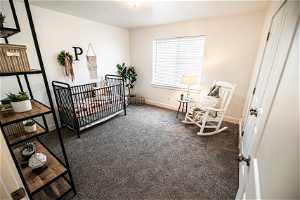 Bedroom with dark colored carpet and a crib