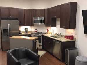 Kitchen featuring a kitchen island, dark brown cabinets, stainless steel appliances, and dark hardwood / wood-style floors