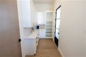 Interior space featuring white cabinetry, backsplash, and light hardwood / wood-style floors