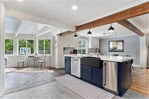 Kitchen featuring blue cabinetry, beamed ceiling, dishwasher, white cabinets, and pendant lighting