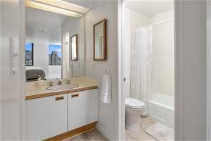 Full bathroom with hardwood / wood-style flooring, shower / bath combination with curtain, toilet, and vanity with extensive cabinet space