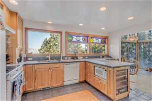 Kitchen with light tile flooring, sink, white appliances, light brown cabinetry, and backsplash
