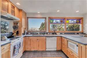 Kitchen featuring sink, white appliances, backsplash, and dark tile floors