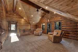 Unfurnished living room with rustic walls, ceiling fan, carpet, and wood ceiling