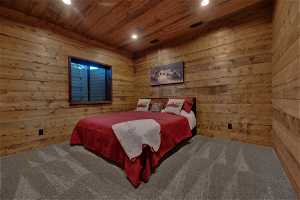 Bedroom with wood walls, wooden ceiling, and carpet floors
