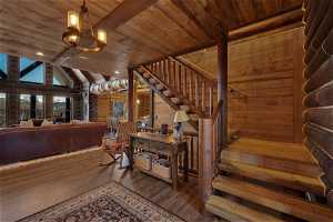 Stairs featuring dark hardwood / wood-style flooring, a chandelier, wood ceiling, and lofted ceiling with beams