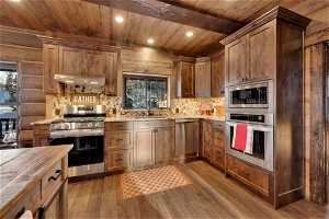 Kitchen with wooden counters, rustic walls, light hardwood / wood-style floors, wooden ceiling, and appliances with stainless steel finishes