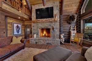 Living room with dark wood-type flooring, a fireplace, rustic walls, and high vaulted ceiling