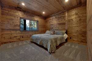 Bedroom featuring wooden walls, carpet floors, and wooden ceiling