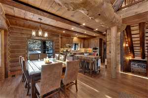 Dining room with dark hardwood / wood-style flooring, rustic walls, a notable chandelier, and wood ceiling