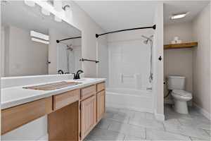 Full bathroom featuring oversized vanity, bathing tub / shower combination, toilet, and tile flooring