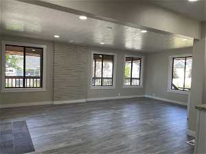 Empty room featuring dark hardwood / wood-style flooring, a textured ceiling, and plenty of natural light