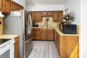 Kitchen featuring stainless steel dishwasher, sink, electric range, and light hardwood / wood-style flooring