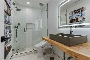 Bathroom with a shower with shower door, vanity with extensive cabinet space, tile floors, and toilet